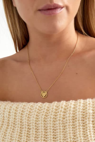 Złoty naszyjnik z sercem na szyi kobiety.